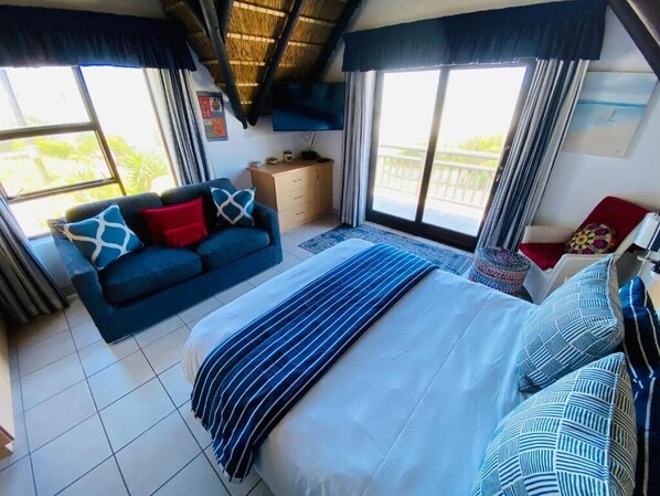 A bedroom with a bed, a sofa, a TV, and a window with a view.