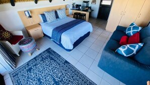 Een slaapkamer met een bed, een bureau, een stoel, een bank en een klein krukje.