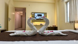 A hotel room with a bed, a TV on the wall, and a door leading to another room. - Hotel Moon Light  (Indore)