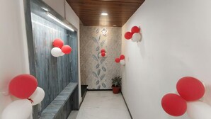 A hallway with a wooden ceiling, a marble floor, and a potted plant. - Hotel Moon Light  (Indore)