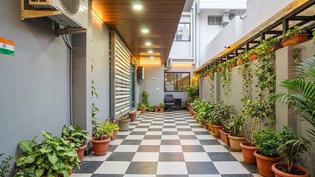 A corridor with a checkered floor, potted plants, and a staircase with a railing. - Hotel Moon Light  (Indore)