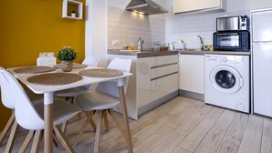 Una cocina moderna con armarios blancos, horno empotrado, microondas y lavadora.