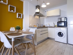 A modern kitchen with white cabinets, a built-in oven, a microwave, and a washing machine. - Sunstay Benalbeach Flat I Benalmadena (Benalmádena)