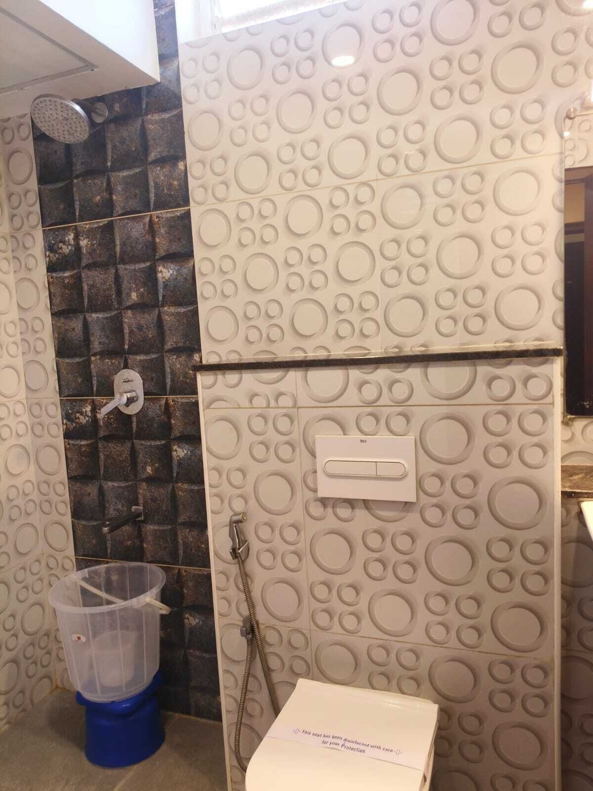 Un bagno con doccia, servizi igienici e una parete decorata con motivi circolari.