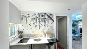 Una cocina moderna con una isla central, un mural decorativo y vistas a un comedor.