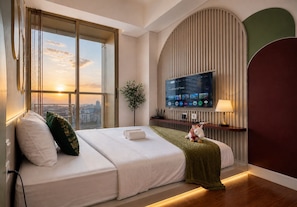 Een hotelkamer met een groot bed, een televisie, een plant en uitzicht op de stad.