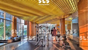 A modern gym with a wooden ceiling, large windows, and various exercise equipment. - Arlo By SanLiving - 2BR - HubLife Mall (Jakarta)