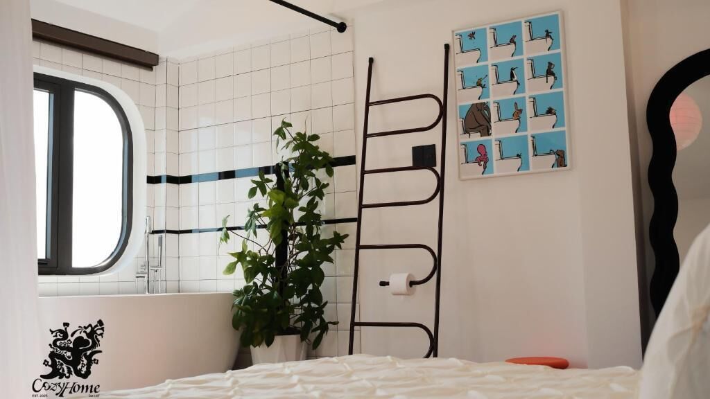 Une salle de bain équipée d’une baignoire, d’une fenêtre, d’une plante, d’un porte-serviettes et d’un support à papier toilette fixé au mur.