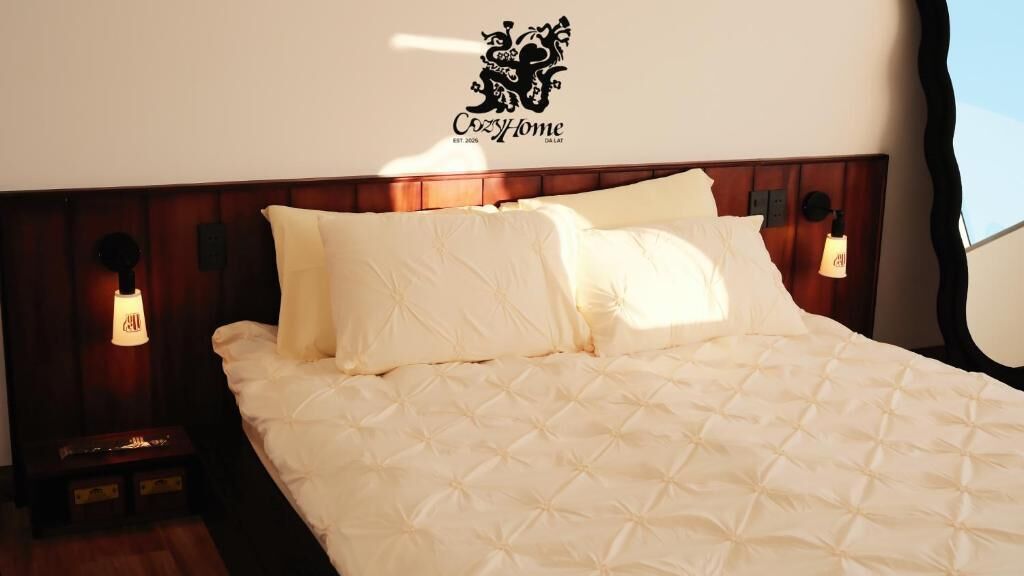A neatly made bed with a quilted white duvet, two pillows, and a headboard with a logo.