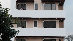 Un immeuble à plusieurs étages doté de balcons, de grandes fenêtres et d’un espace extérieur aménagé pour s’asseoir.