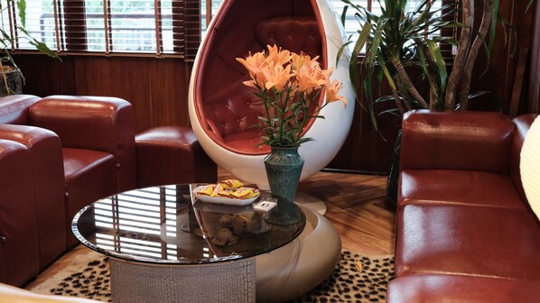 Ein modernes Wohnzimmer mit Ledersofas, einem Glastisch, einer Blumenvase und einem Topfpflanzen.