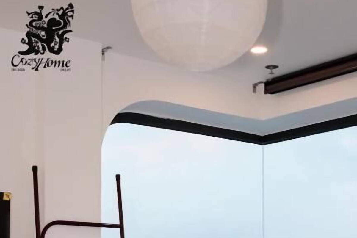 Una camera da letto con un'ampia finestra, una scala in metallo, una pianta in vaso e un letto.