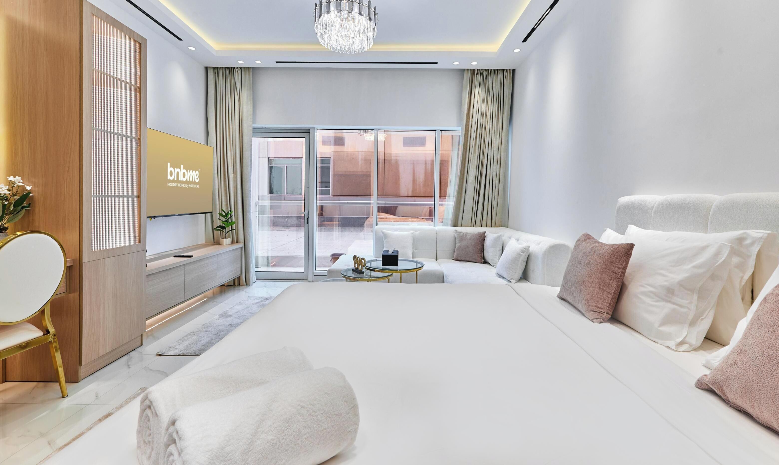 Une chambre d’hôtel moderne dotée d’un grand lit, d’un canapé, d’une petite table, d’une télévision et d’un balcon avec vue.