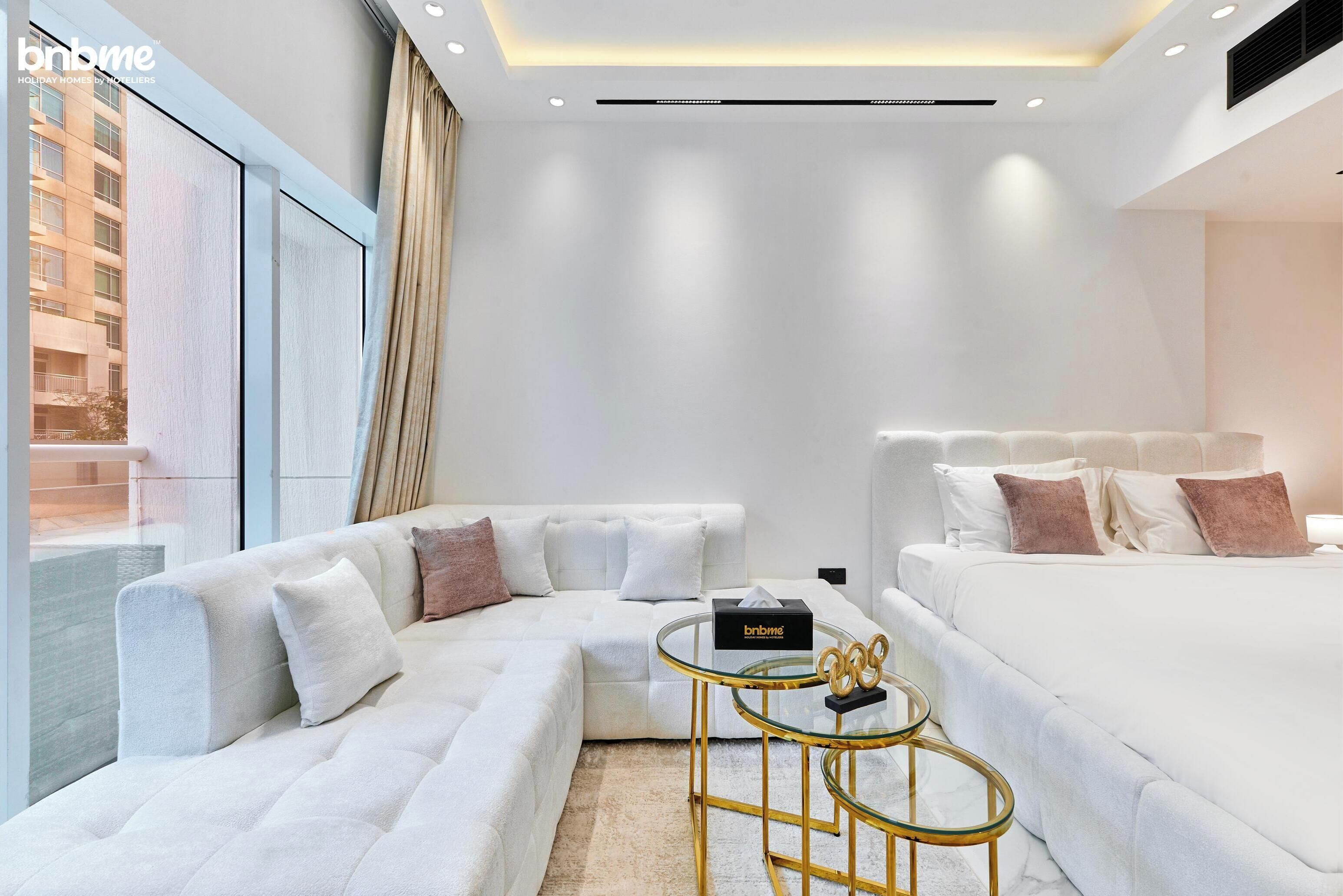 A modern hotel room with a large bed, a sofa, and a small table.