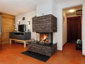 Un salon avec une cheminée en pierre, un téléviseur et un meuble en bois.