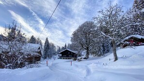 Een besneeuwde ski-resort met een lodge, bomen en een heldere lucht.