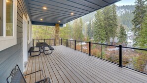 A wooden deck with a railing, a table, and chairs. - Mountain Retreat By the River: Star Valley Getaway (Afton)
