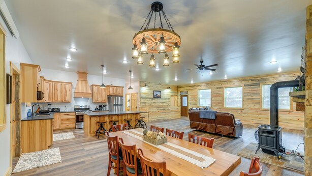 A spacious kitchen with wooden cabinets, a central island, and a dining area with a large wooden table and chairs. - Mountain Retreat By the River: Star Valley Getaway (Afton)
