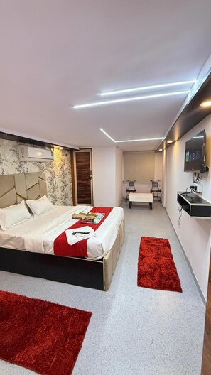 Una camera da letto moderna con un letto grande, una scrivania piccola, un televisore e un tappeto rosso.