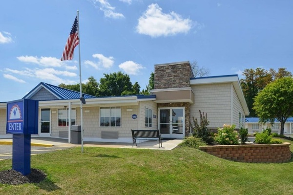 Step into a welcoming entrance surrounded by sunny, landscaped grounds.
