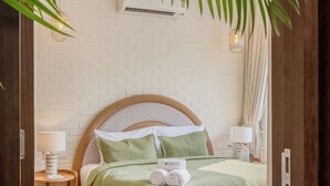 Une chambre à coucher bien rangée, avec un lit, une table de chevet et une lampe.