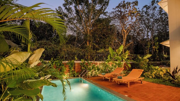 Une piscine dotée de chaises longues et agrémentée de plantes tropicales.
