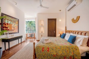 A well-lit bedroom with a bed, bedside lamps, a wooden headboard, and a view of the outdoors. - Vida Pacifica Villa (Verla Canca)