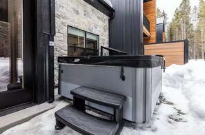 A modern building with a stone facade, a wooden deck, and a hot tub. - New, hotTub, kid'sToys, AC, EV Charger, close2YNP! (Island Park)