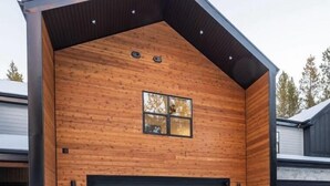 En moderne bygning med træfacade, stor garageport og et lille vindue.