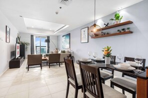A modern dining area with a round table set for four, surrounded by wooden chairs. - StayShort - Modern 2BR in Dubai Marina that Sleeps 6 (Dubai Marina)