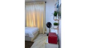 Una camera da letto con un letto, una ventola, un termosifone rosso e uno scaffale con piante.