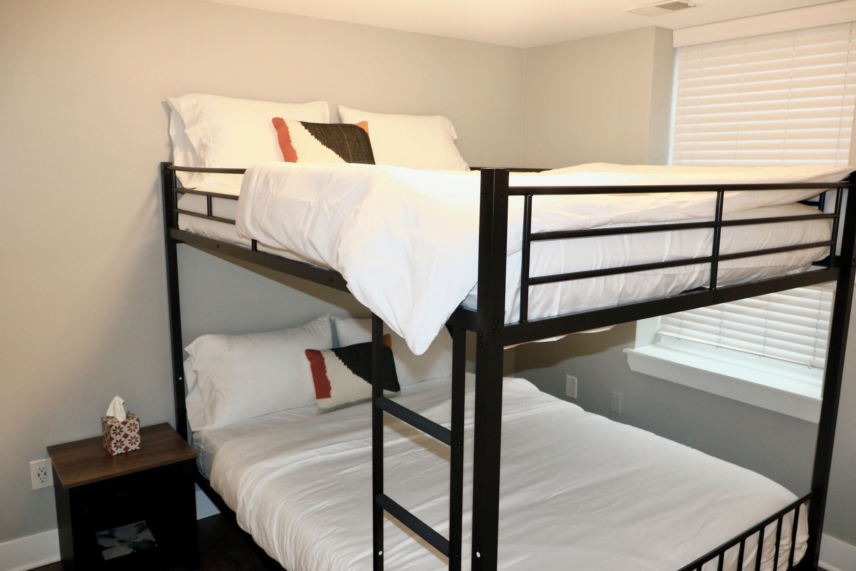 A bunk bed room with a window and a bedside table.