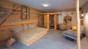 A wooden room with a bed, a small table, and a sauna.