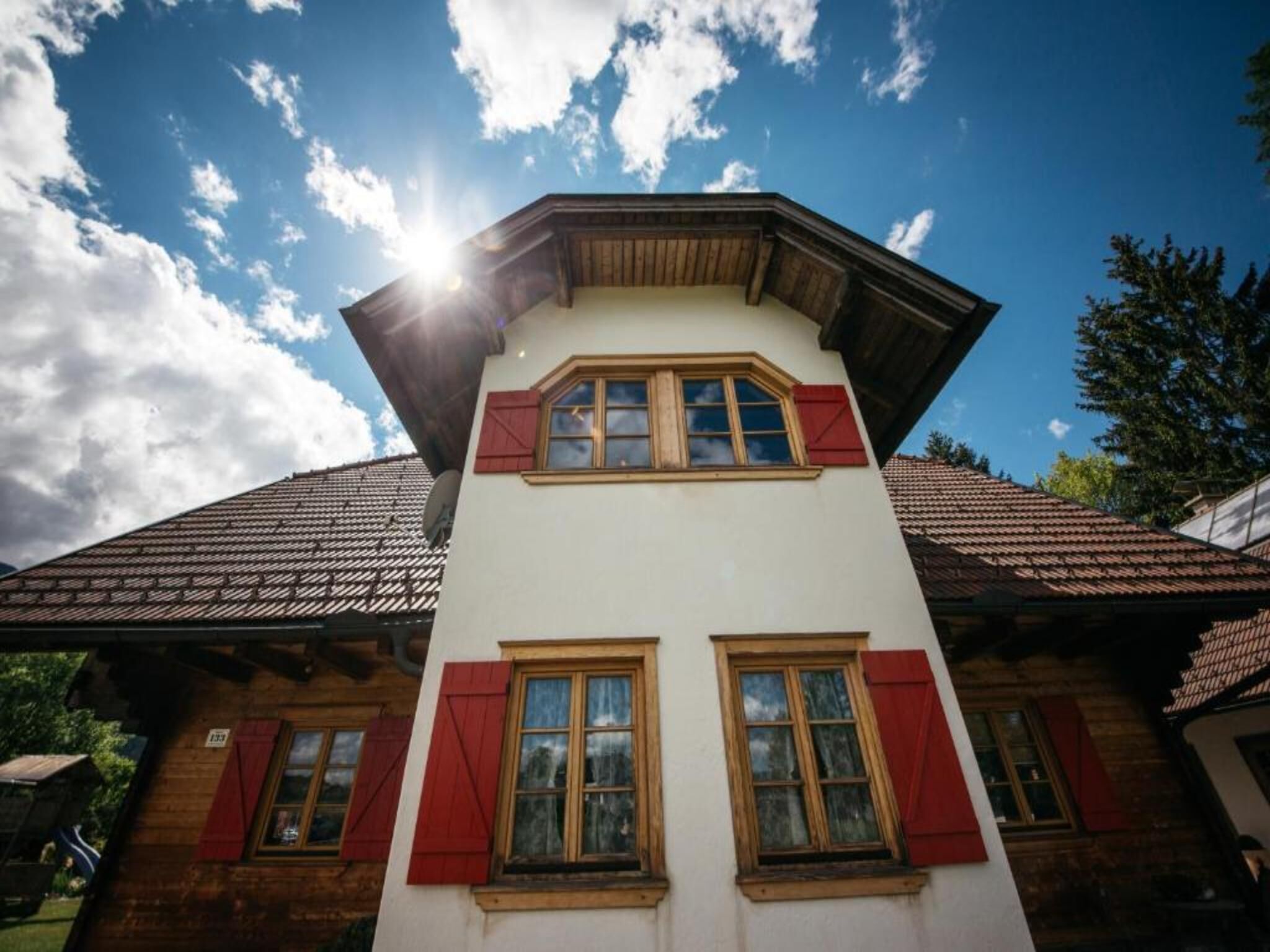 A two-story building with a sloped roof, red shutters, and a clear sky.