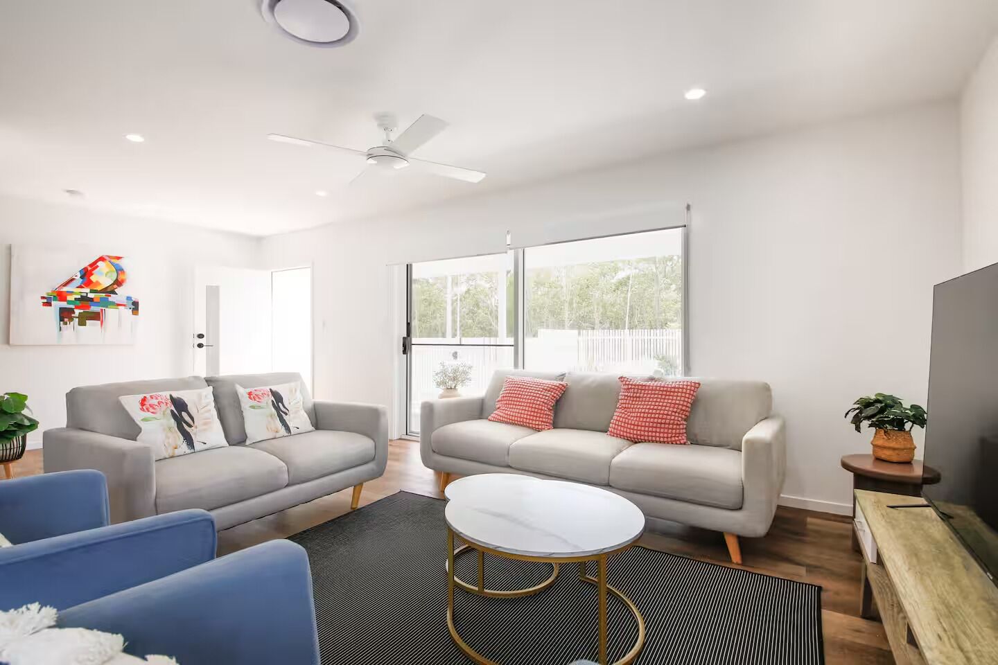 Un salon moderne avec deux canapés, une table basse et un ventilateur de plafond.