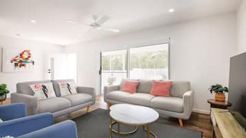A modern living room with two sofas, a coffee table, and a ceiling fan.
