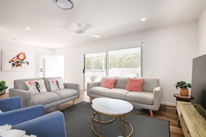 A modern living room with two sofas, a coffee table, and a ceiling fan. - Brand new 3BR townhouse -Modern comfy family home (Rochedale)