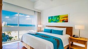 A hotel room with a large window, a bed with blue bedding, a nightstand with a phone, and a painting on the wall. - Hotel Almirante Cartagena Colombia (Cartagena)