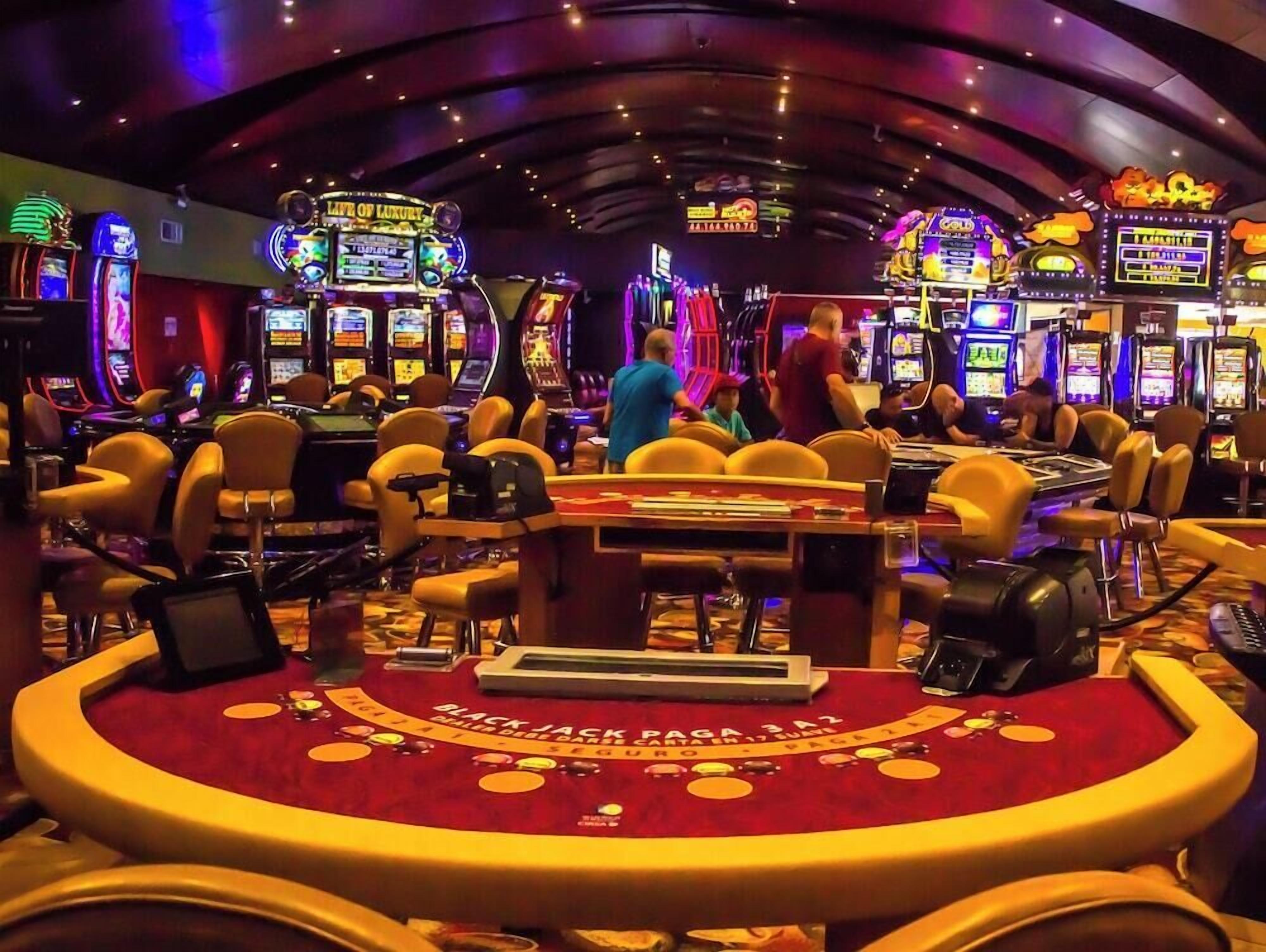 A casino with multiple slot machines, blackjack tables, and a vibrant atmosphere.