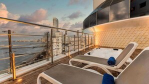 A rooftop lounge with two sun loungers, a view of the city skyline, and a river. - Hotel Almirante Cartagena Colombia (Cartagena)