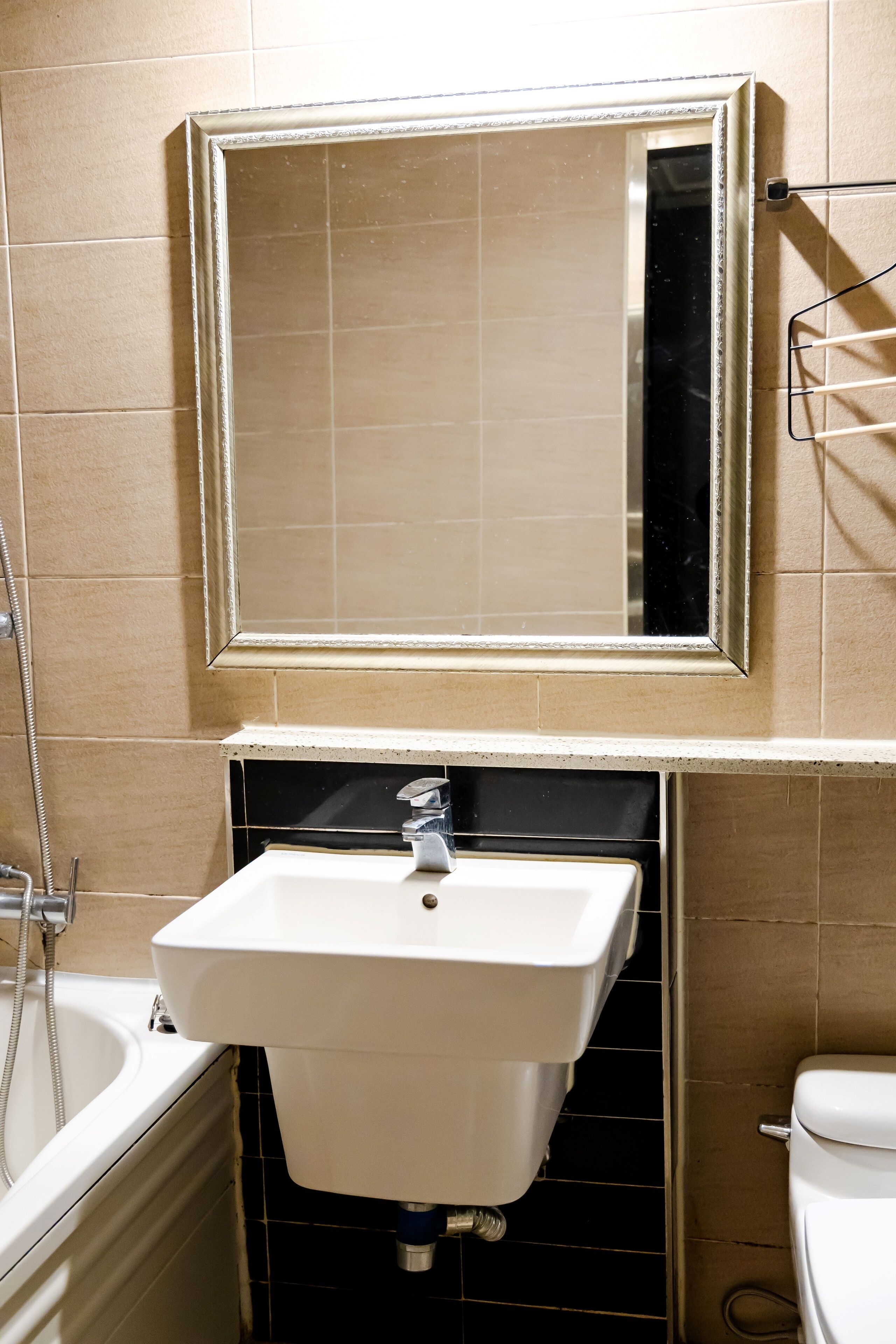 A bathroom with a white sink, a mirror above it, and a toilet to the right.