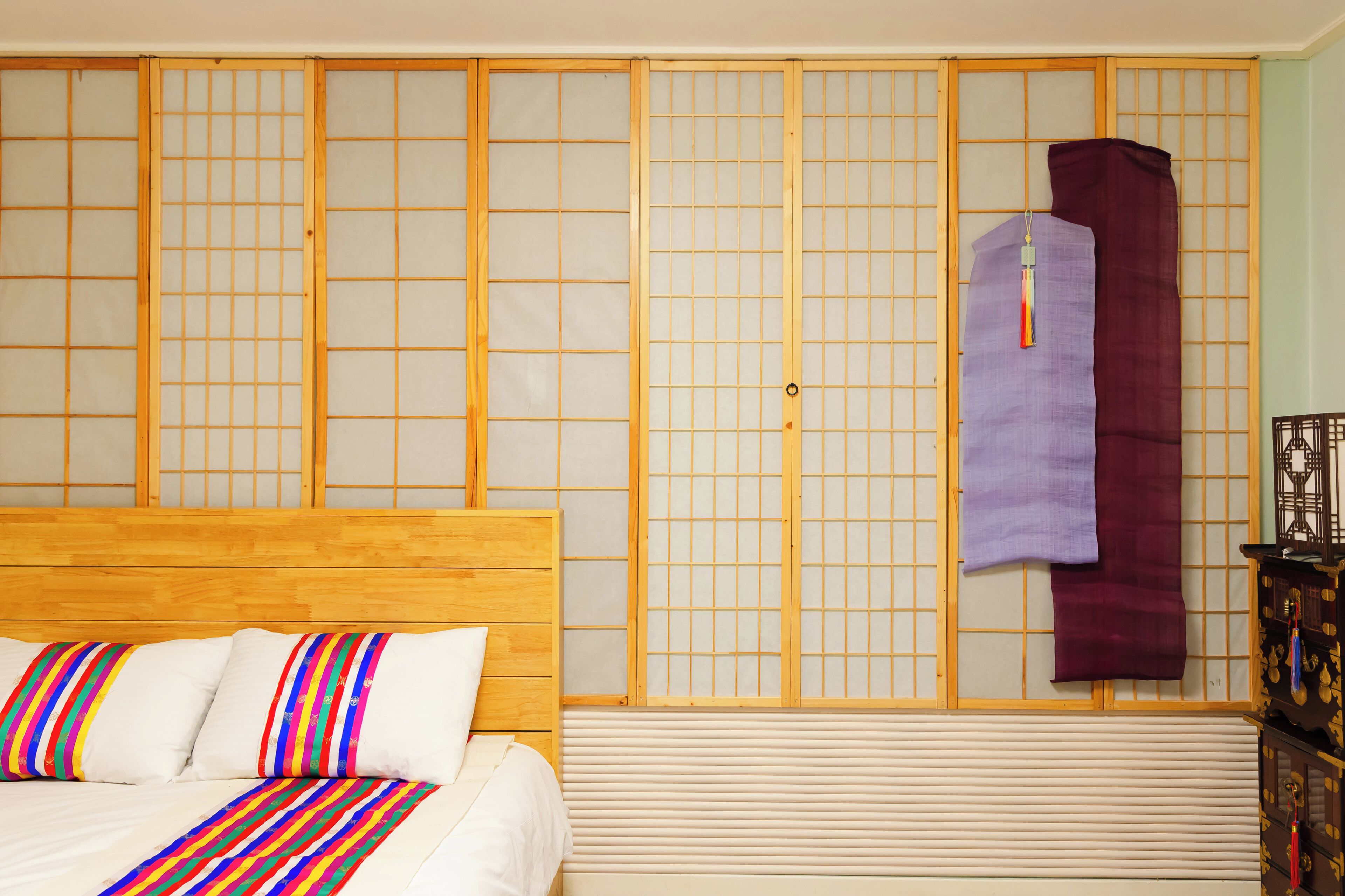 Una habitación tradicional japonesa con cama de madera, biombos shoji y futón.