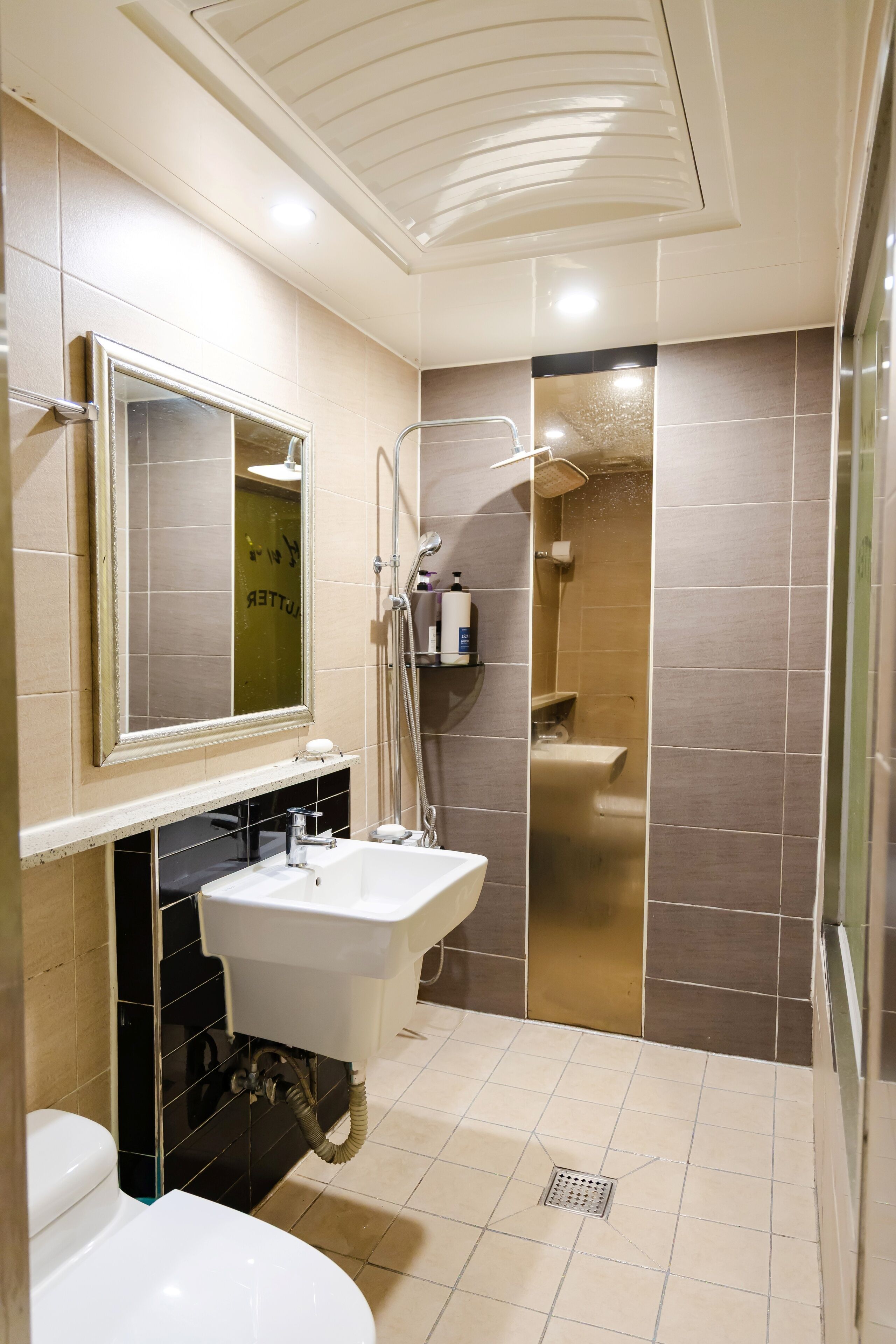 A modern bathroom with a white sink, a mirror, a toilet, and a shower area.