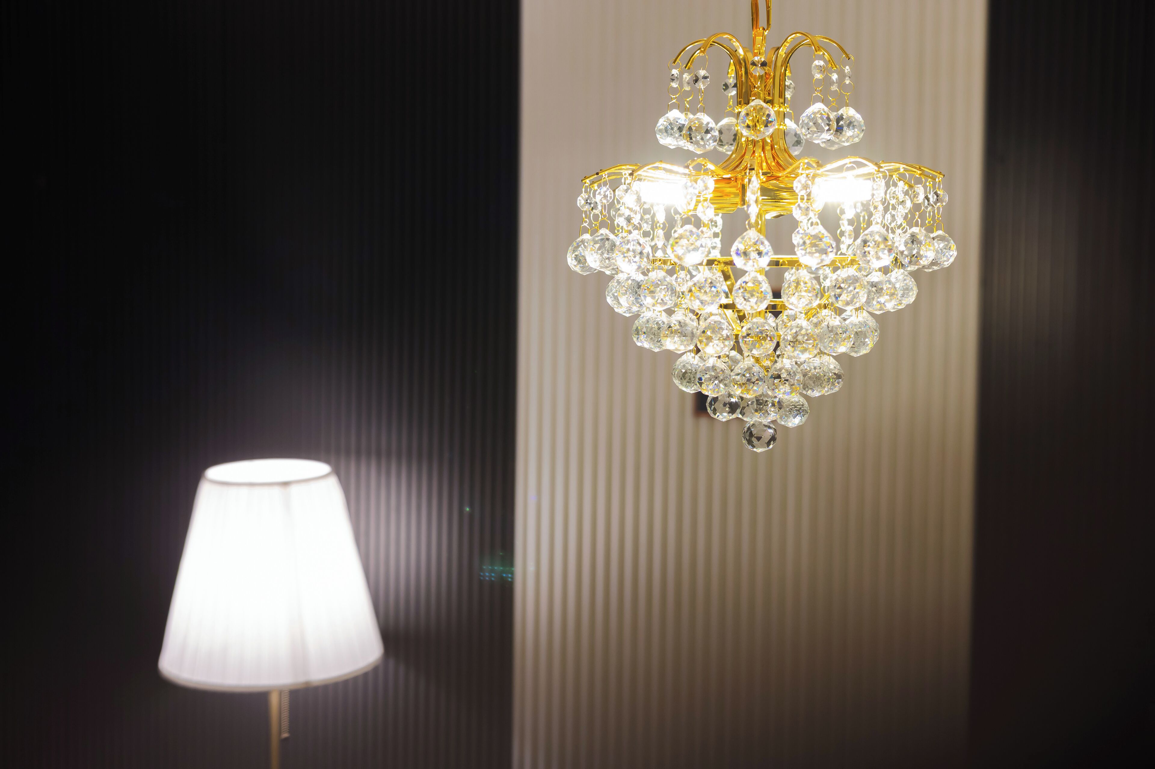 Un candelabro con múltiples detalles de cristal y una lámpara con pantalla blanca.