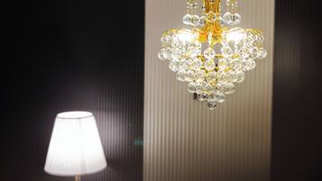 Un candelabro con múltiples detalles de cristal y una lámpara con pantalla blanca.