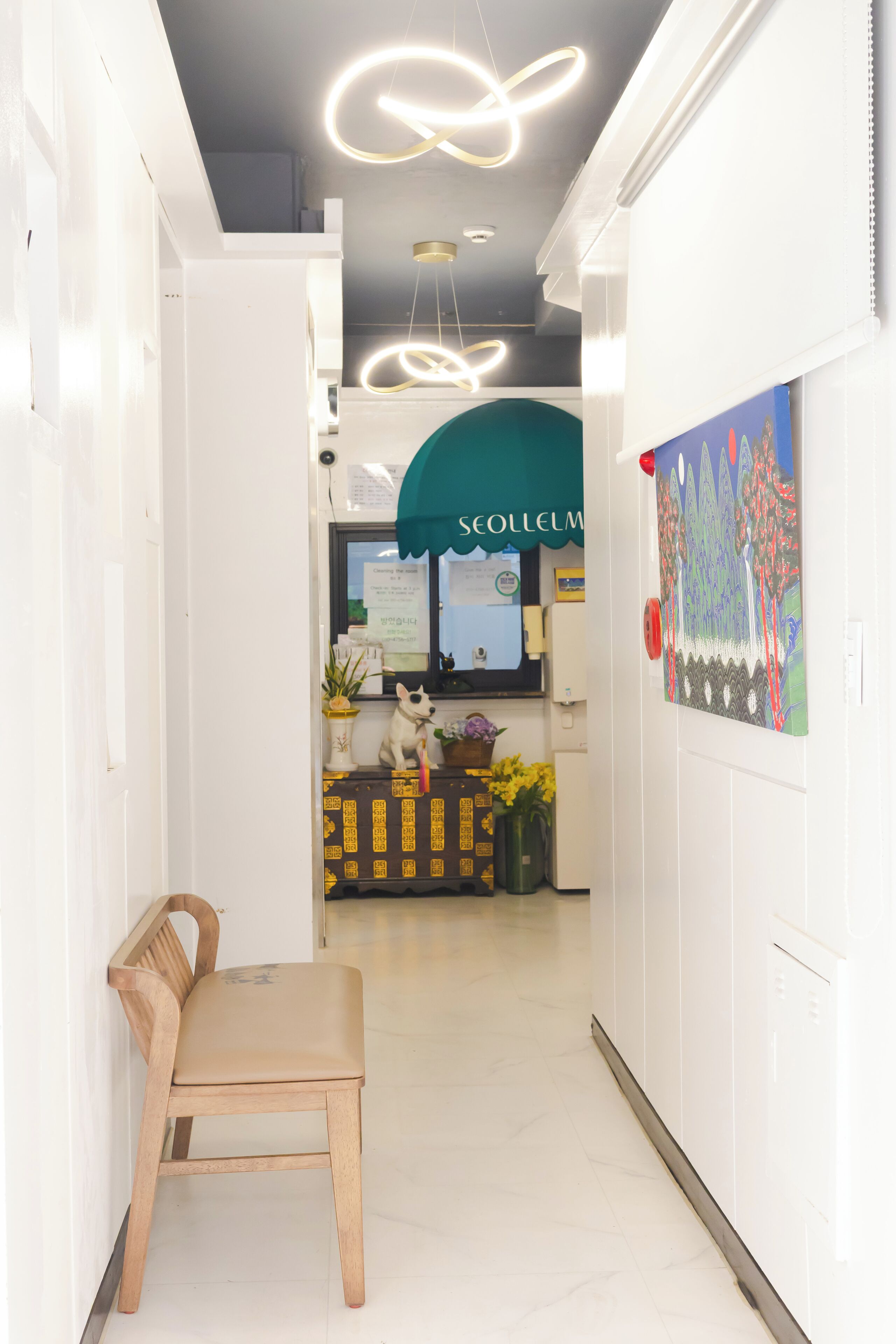 A reception area with a wooden bench, a reception desk, a green awning, and a wall-mounted painting.