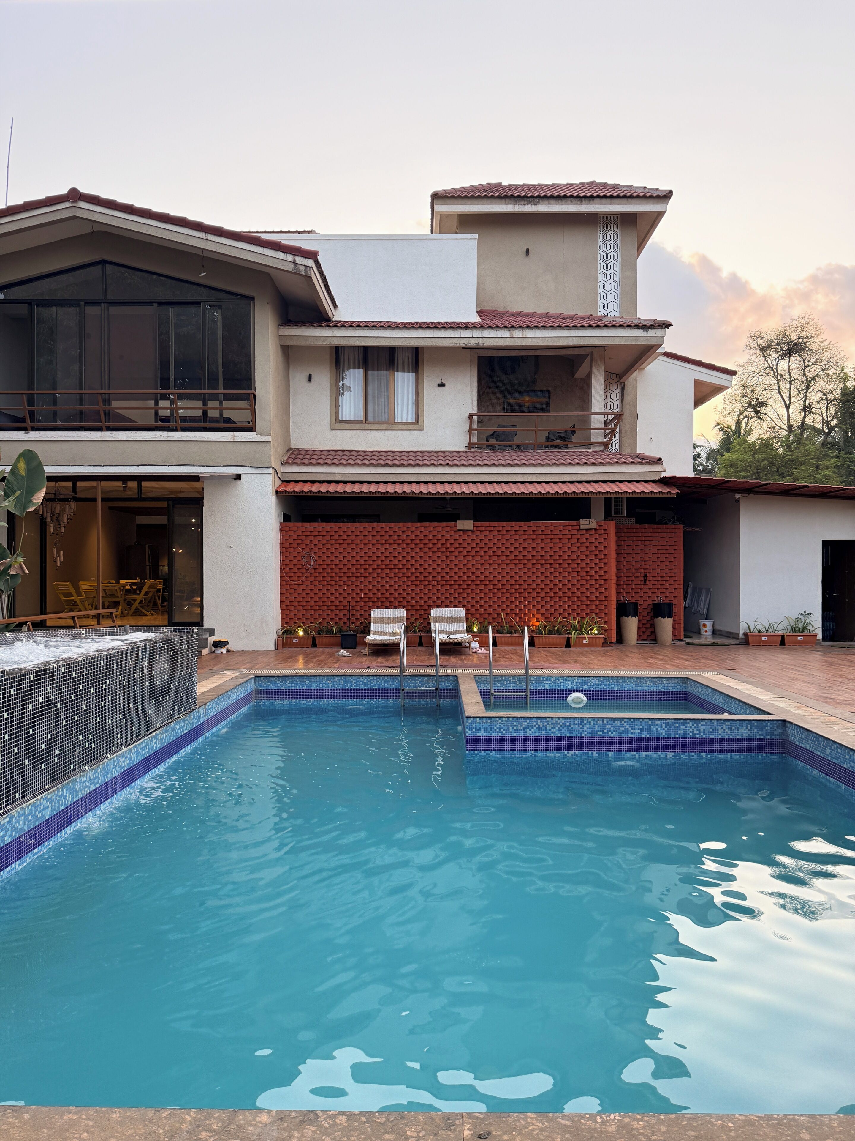 A modern house with a swimming pool, a balcony, and a brick wall.