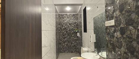 A modern bathroom with a marble shower wall, a large sink, and a bathtub.