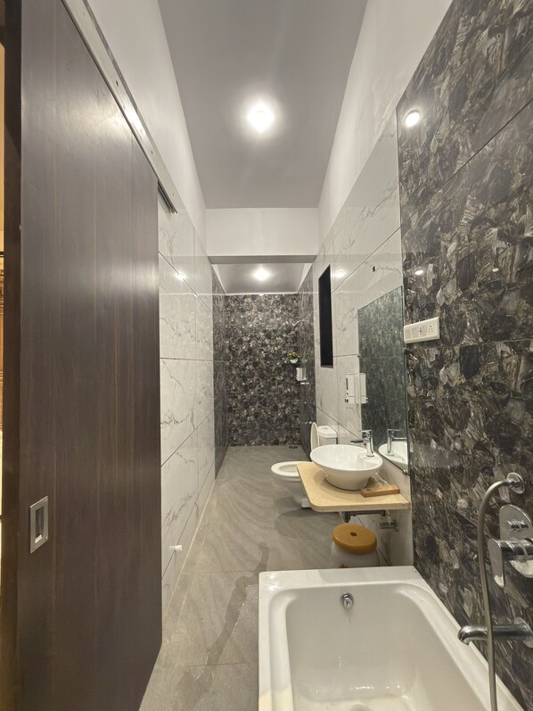 Une salle de bain moderne avec un mur de douche en marbre, un grand lavabo et une baignoire.