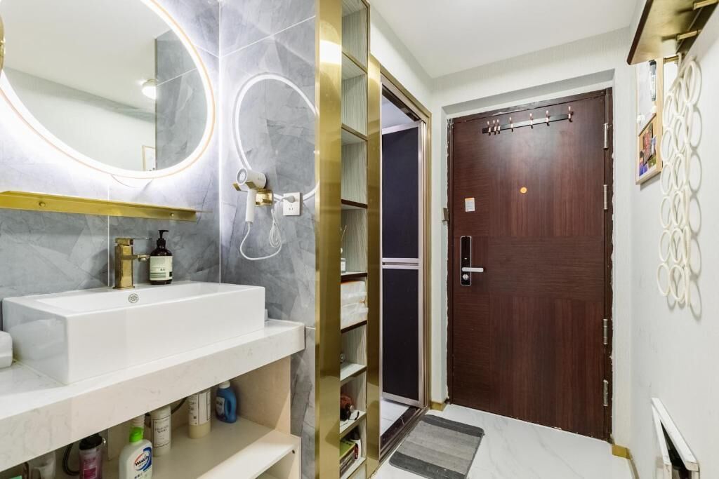 A bathroom with a white sink, a large mirror with a gold frame, and a wooden door.